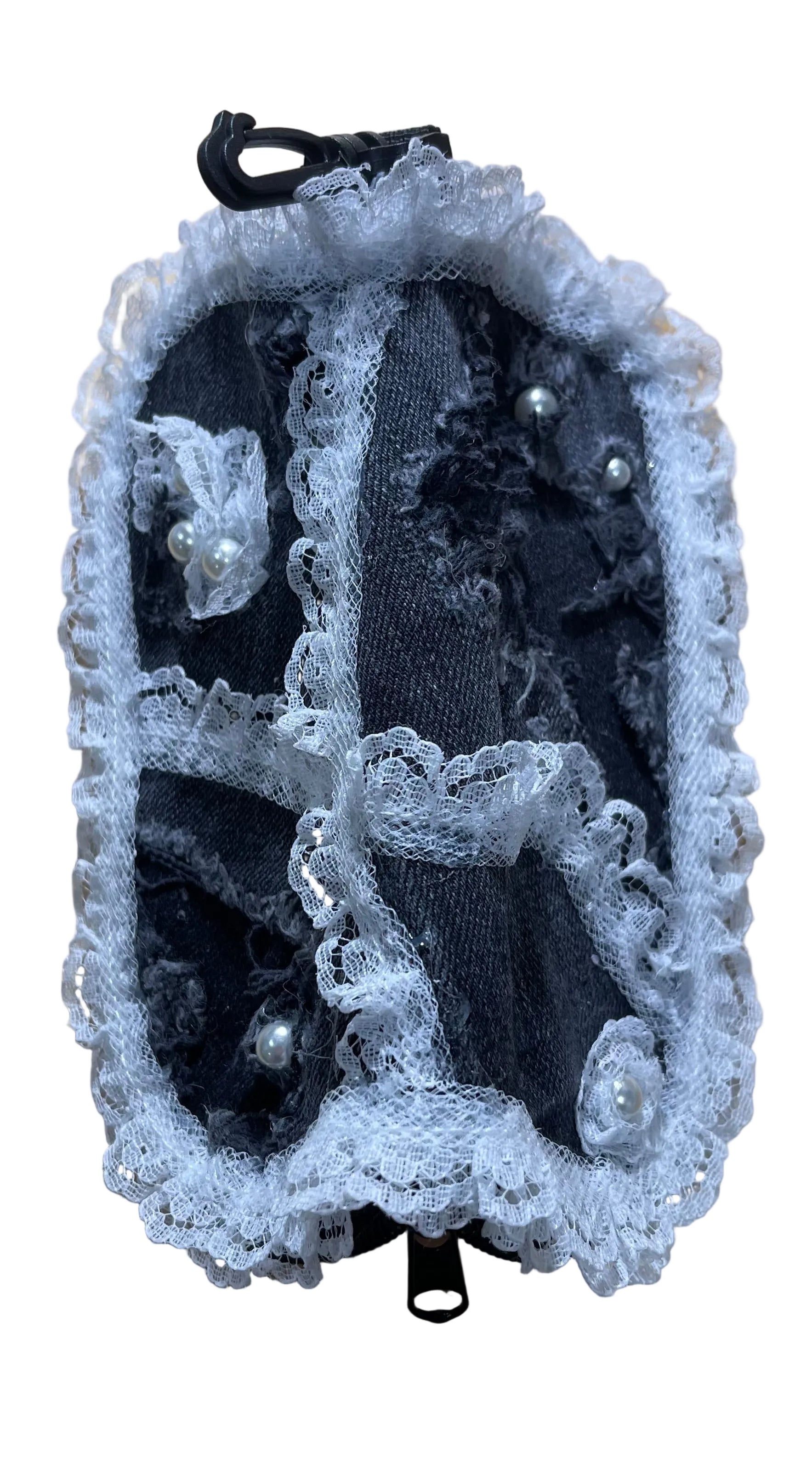 Black shoe with white lace and pearls on a wooden surface